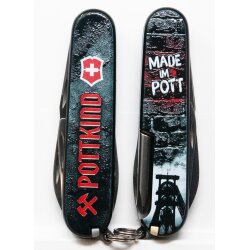 Victorinox Tinker Pottkind Taschenmesser Griffschale Rückseite in grauer Backsteinwand Optik mit schwarzem Förderturm Motiv unter bewölktem Himmel